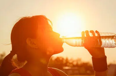 Femme buvant d une bouteille d eau pendant le coucher du soleil - coup de chaleur exercices soportif | IK Paris