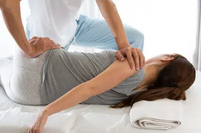 Kinesitherapeute aidant une femme pour les etirements du bassin - fracture bassin | IK Paris